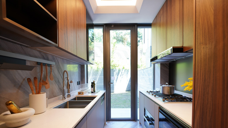 Sleek galley kitchen with wooden cabinetry and marble backsplash