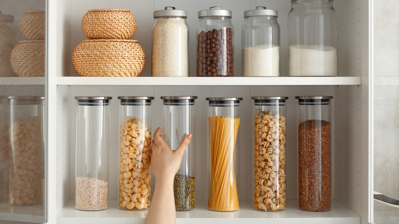 Hand reaching for jar from neatly organized kitchen cabinet
