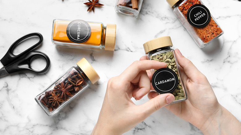 Hand labeling a spice bottle on a marble tabletop