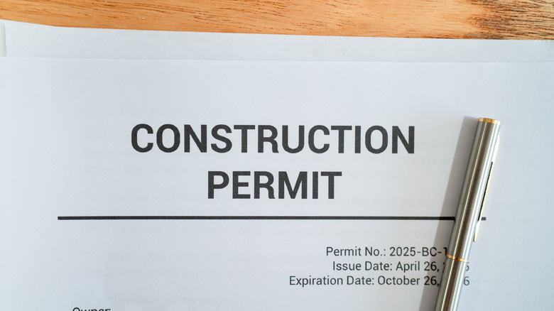 Paper with construction permit placed on a wooden table