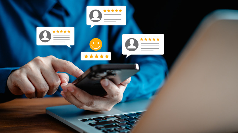 Man's hand holding a phone with several blurbs showing five-star ratings