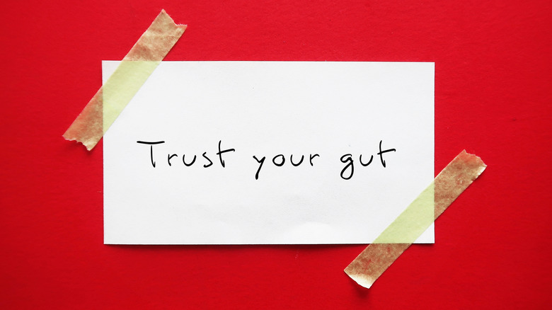Paper with the words "trust your gut" taped to a red background