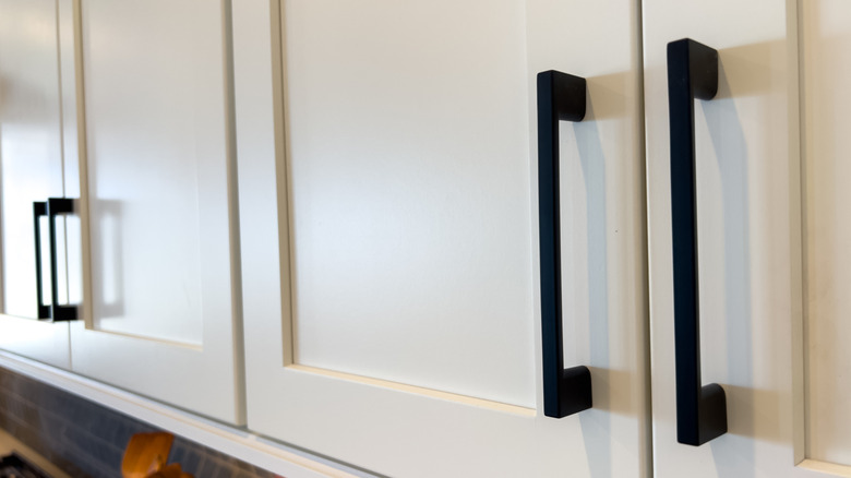 Black vertical cabinet handles on white cabinets