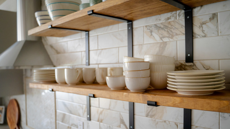 Close-up of open shelves stacked with plates, bowls, and cups