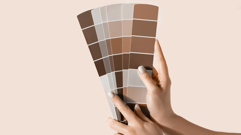 Hand holding several color swatches of Pantone color of the year, mocha mousse