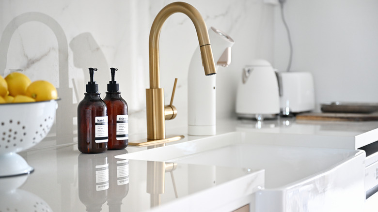 Close-up shot of a kitchen sink with marble countertop and backsplash