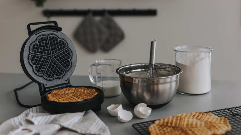 Waffles and waffle maker placed on kitchen counter