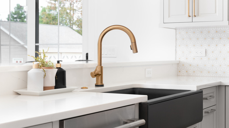 Interior shot of light kitchen counters with a dark farmhouse sink