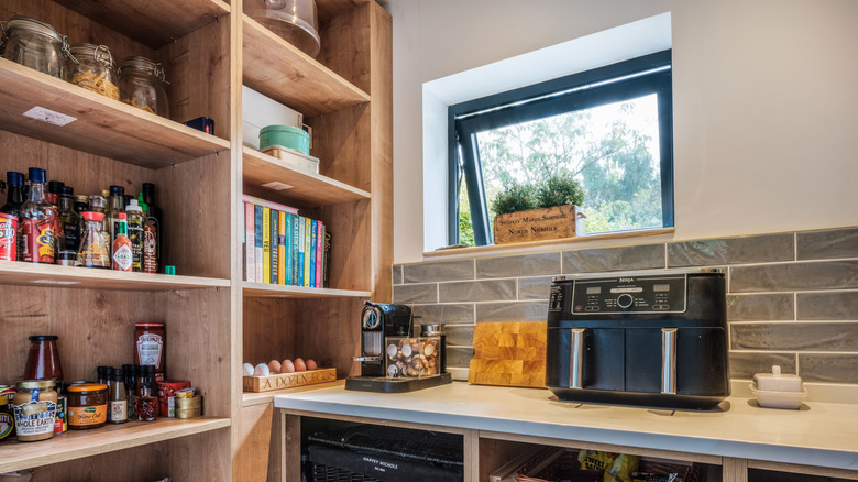 Close-up of a stocked wooden pantry in an L-shaped kitchen