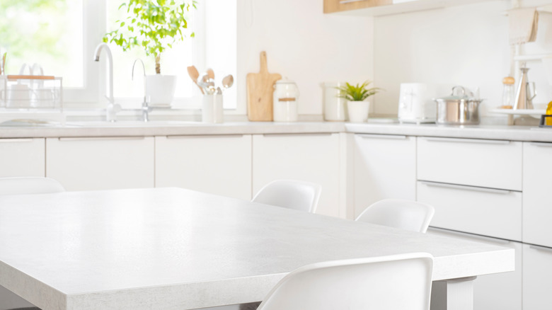 Empty dining table placed in a bright kitchen with white cabinetry