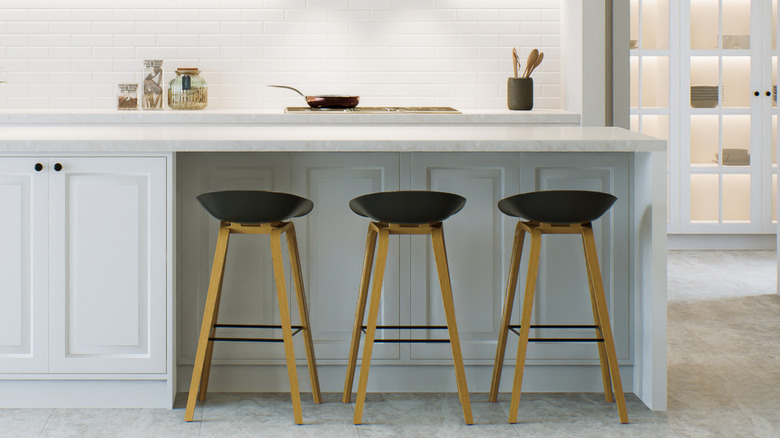 Three bar stools placed under a white kitchen island