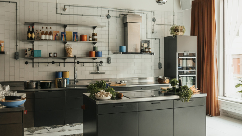 Kitchen interior with white tiled walls, dark cabinets, and an island