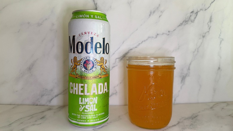 Can of Modelo Chelada Limon y Sal next to glass of beer on marble surface