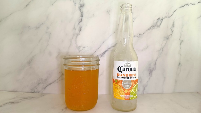 Bottle of Corona Sunbrew Citrus Cerveza next to glass of beer on marble surface