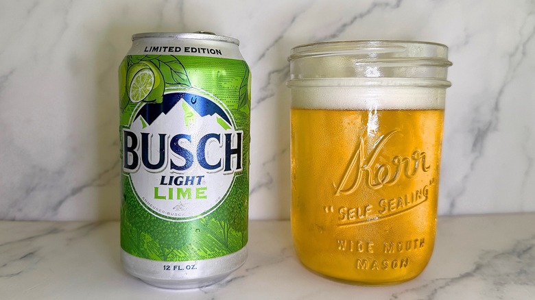 Can of Busch Light Lime next to glass of beer on marble surface