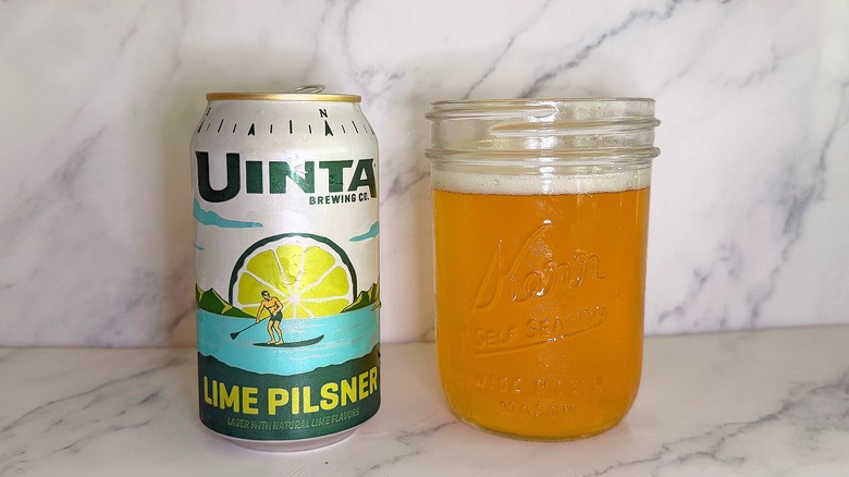 Can of Uinta Lime Pilsner next to glass of beer on marble surface