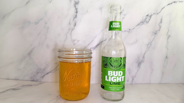 Bottle of Bud Light Lime next to glass of beer on marble surface