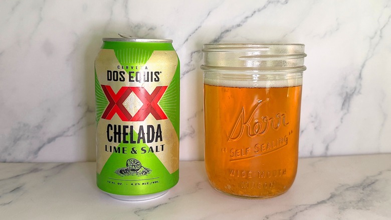 Can of Dos Equis Lime & Salt next to glass of beer on marble surface
