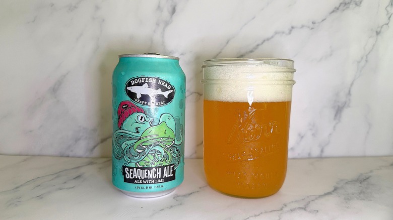 Can of Dogfish Head Seaquench Ale next to glass of beer on marble surface