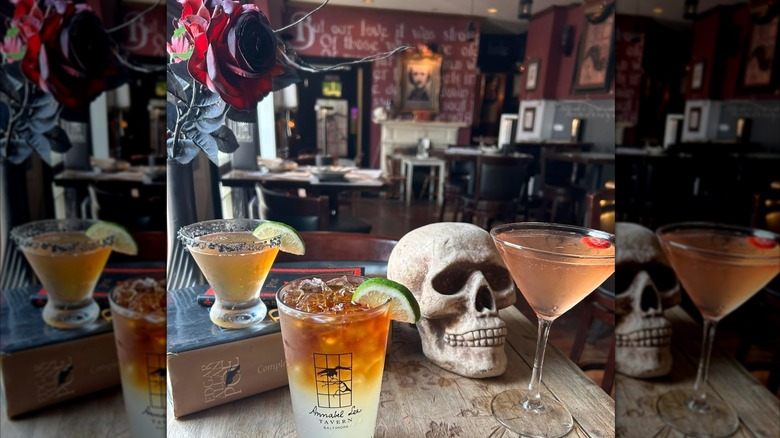 Three cocktails on table alongside Edgar Allen Poe book and fake skull