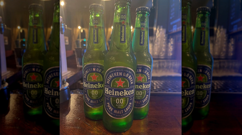 mirror image of three bottles of heineken 0.0 on a counter