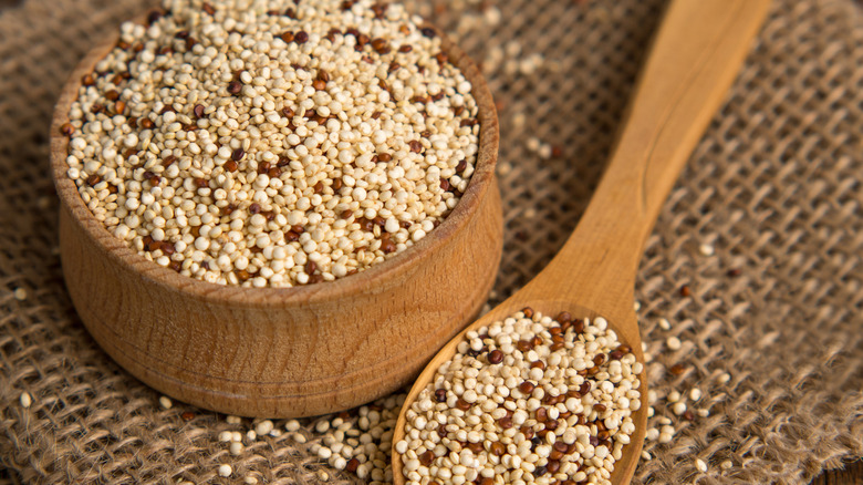 A wooden bowl and spoon full of quinoa grains