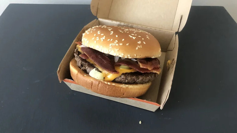 A McDonald's Bacon Quarter Pounder with cheese in its container on a table