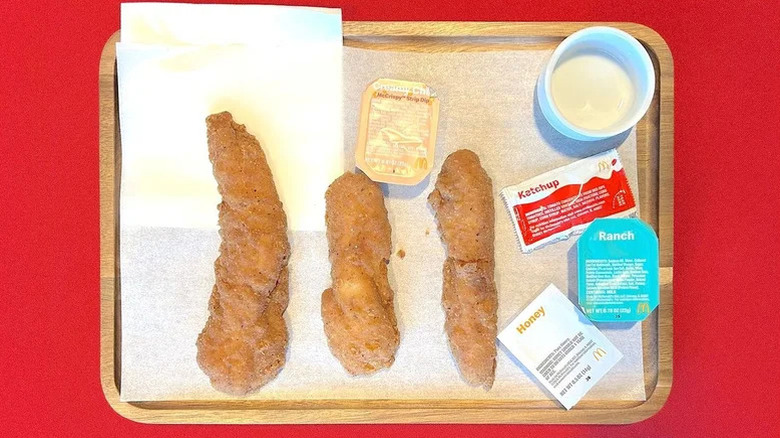 Three McDonald's McCrispy Strips on a restaurant tray next to various sauces