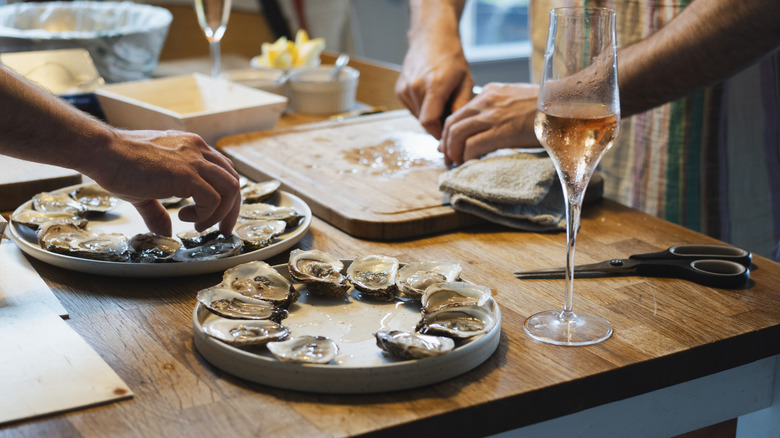 A bottle of champagne and a plate of oysters on a table