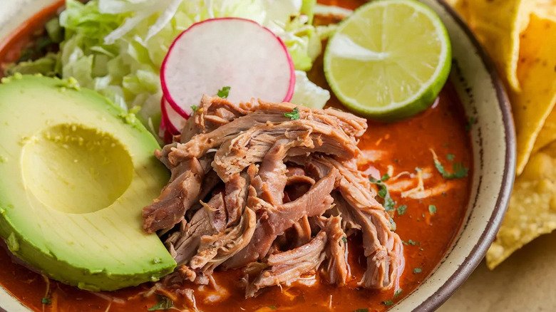 A bowl of pozole with garnishes