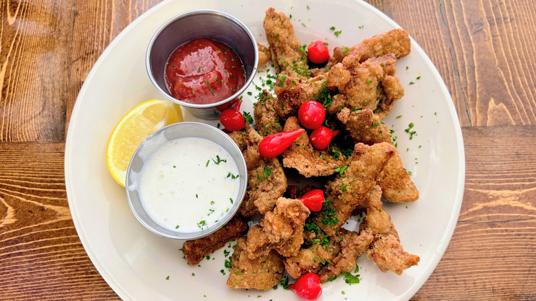Fried Rocky Mountain oysters on a white plate with dipping sauces