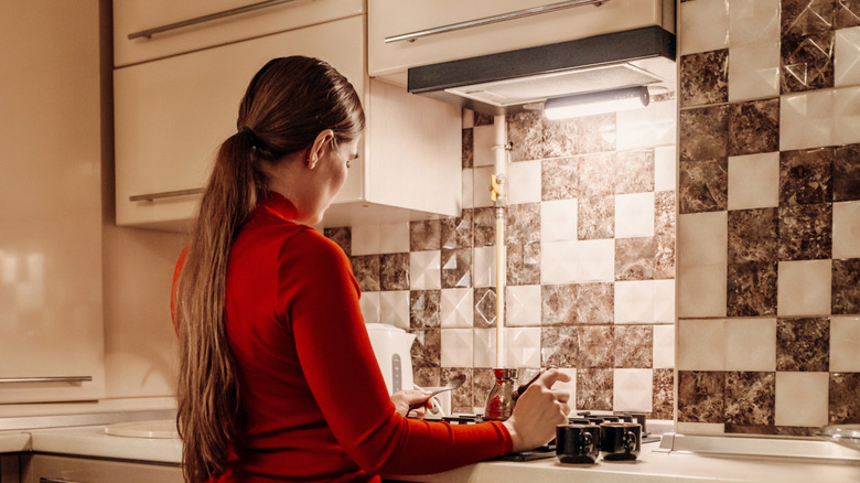 A woman next to a kitchen patterned backsplash