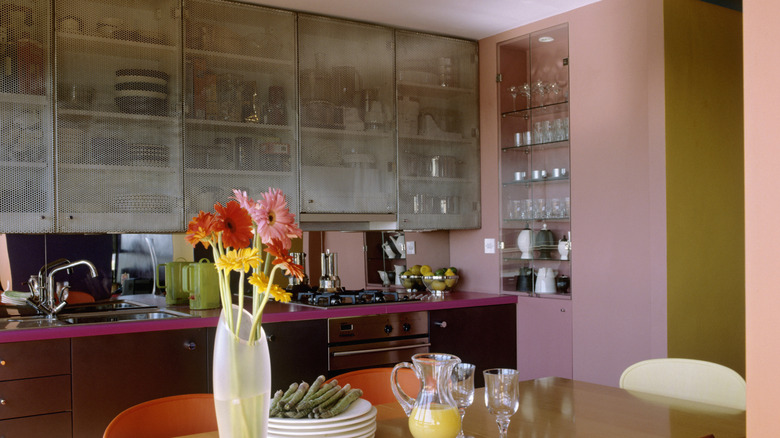 A pink and orange kitchen with display shelves
