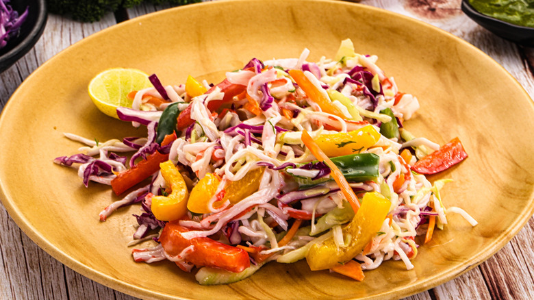 A plate of cabbage salad with peppers and imitation crab