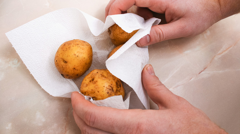 Hands drying potatoes with paper towels