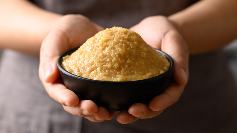 Hand holding black bowl of miso paste