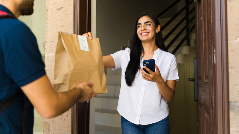 Food delivery driver handing bag to customer