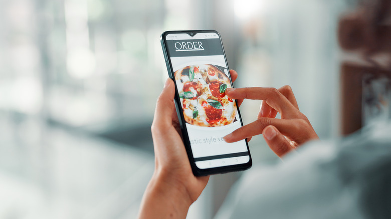 Hands holding phone with restaurant website on screen