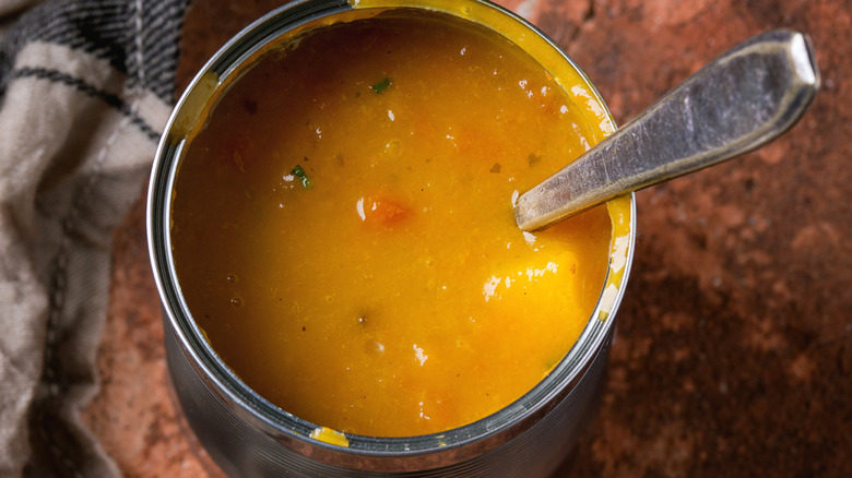 An open can of soup with a spoon sticking out