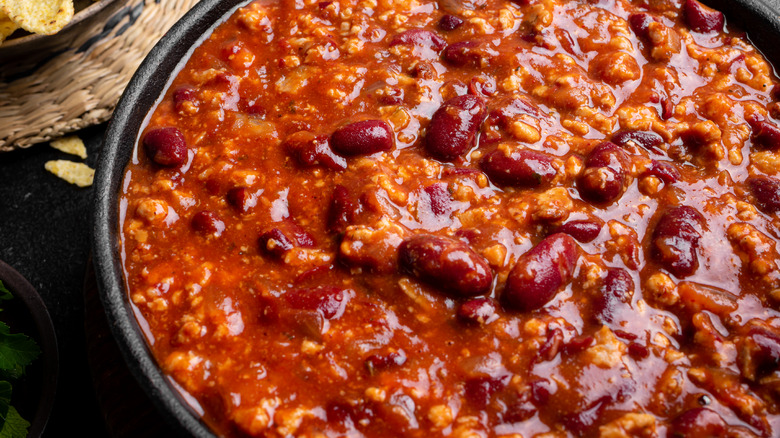 Black bowl of chili with meat and beans