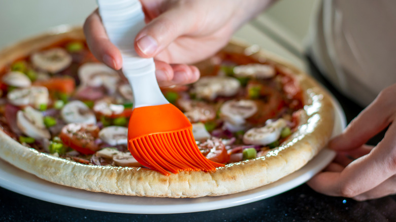 Brushing pizza crust with oil