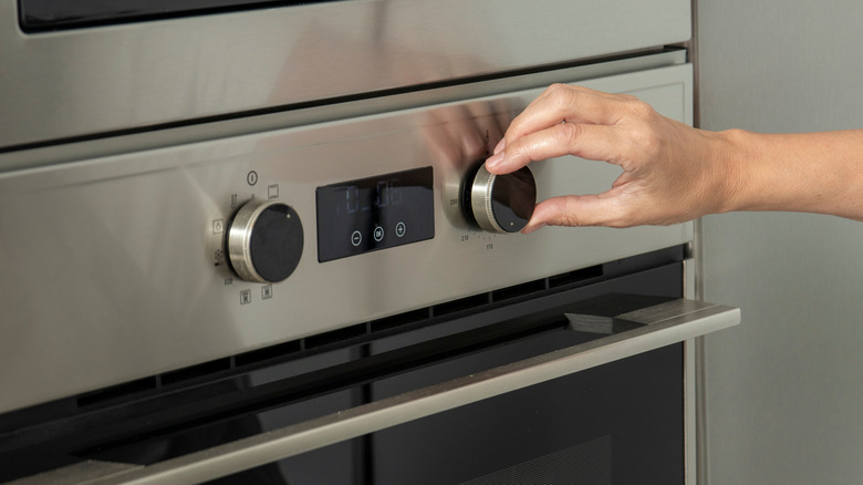 Hand turning dial on stainless steel oven