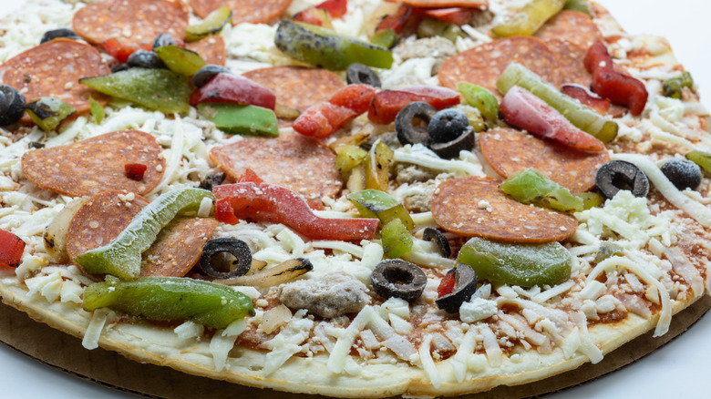 Frozen pizza with pepperoni, bell peppers, and sliced black olives