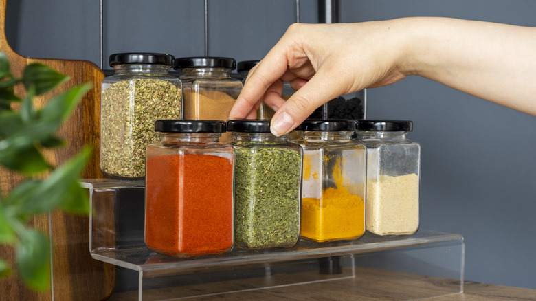 Hand picking jar from rack of herbs and spices