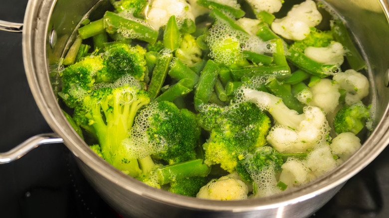 Boiling cauliflower, broccoli, and green beans in saucepan