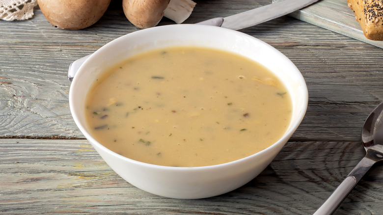 White bowl of cream of mushroom soup on wooden table