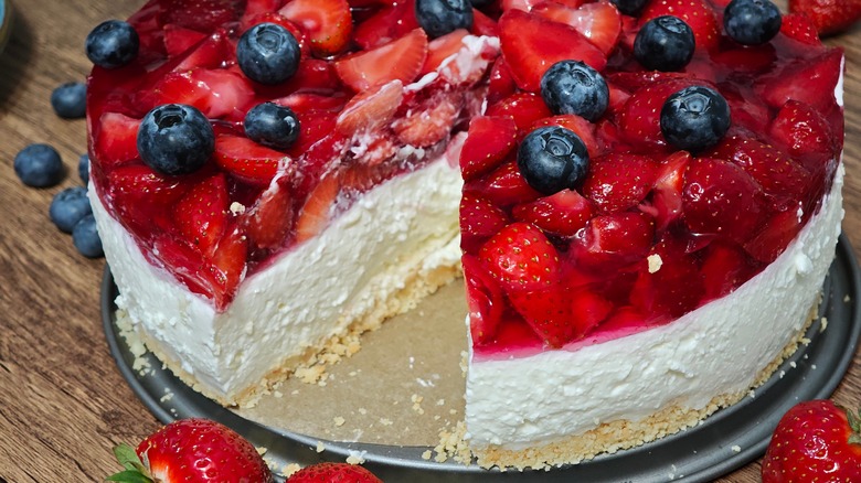 No-bake cheesecake with a fruit filled jelly topping with one slice cut out