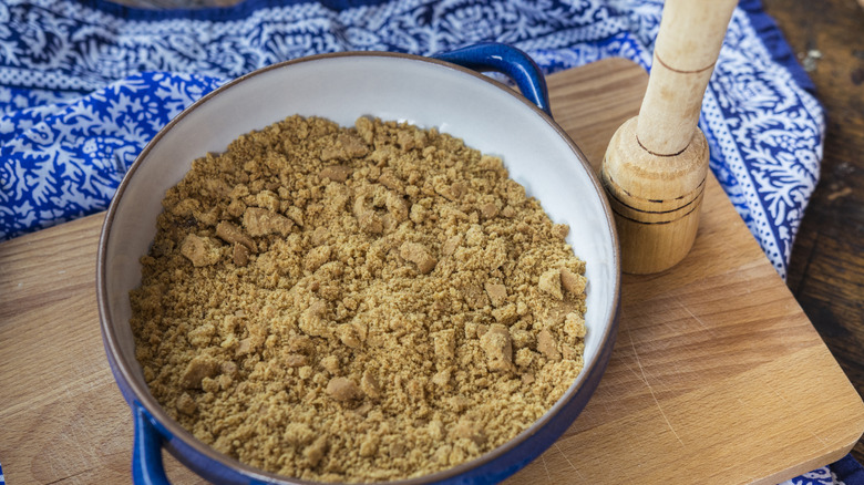 A dish filled with crushed graham crackers on a wooden board