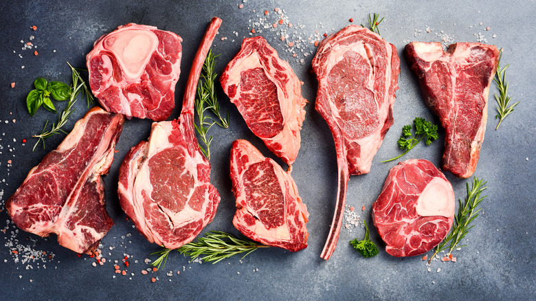 Top view of a variety of raw steak cuts on a black surface