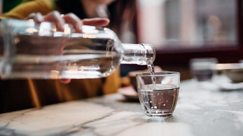 Person pouring water into a glass